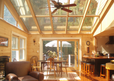 A large sunroom addition built beside this Gloucester kitchen floods the space below with golden sunlight