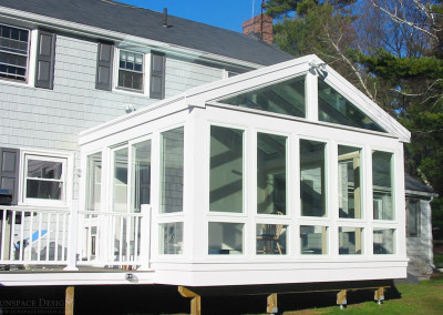 A sunroom built on supports blends seamlessly with this New Hampshire residence and provides both deckside and interior access