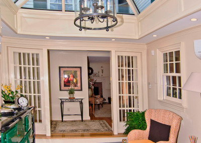 A view of an orangery foyer that connects directly to the home's interior via elegant French doors