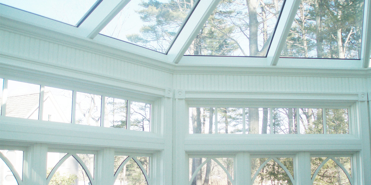 An interior view of a Sunspace Design-built custom Victorian conservatory's glass roof and clerestory windows transmitting sunlight to the interior of the room in Kittery Point, Maine