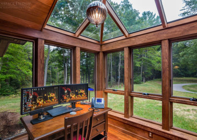Sunlight enters an office space via the roof and window glass of a mahogany framed custom addition