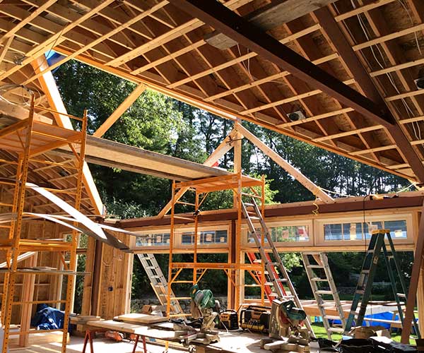 An interior photograph of a brightly lit pool enclosure construction site which reveals the angular shape of the glass roof opening