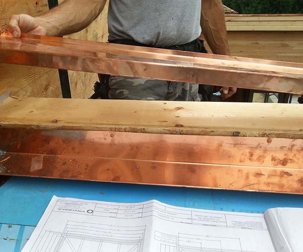 A member of the Sunspace Design team is seen fitting the copper cladding to the skylight frame