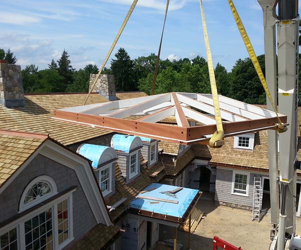 A crane operator is seen lifting the roof section of the skylight into position with expert care