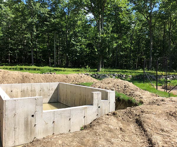A hardened concrete greenhouse foundation is located in this York, Maine backyard and will soon be backfilled and graded